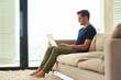 Sofa, home and man with typing on laptop for communication, information and freelance website. Relax, remote work and male person with technology for copywriting, research and digital connection