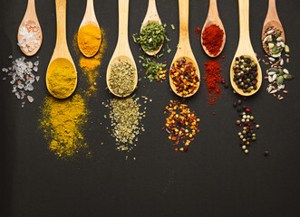 Wall Mural - Various Asian spices in spoons on black background. Top view with free space