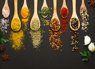 Wall Mural - Various Asian spices in spoons on black background. Top view with free space