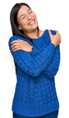 Poster - Young hispanic woman wearing casual clothes hugging oneself happy and positive, smiling confident. self love and self care