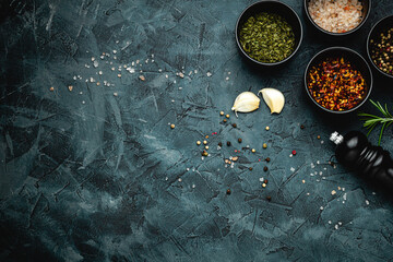 Wall Mural - Dark stone kitchen background with spices, herbs and kitchen utensils. Free space for text. Top view. Rustic style.