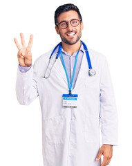 Poster - Young hispanic man wearing doctor uniform and stethoscope showing and pointing up with fingers number three while smiling confident and happy.