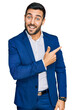 © Krakenimages.com - Young hispanic man wearing business jacket cheerful with a smile on face pointing with hand and finger up to the side with happy and natural expression