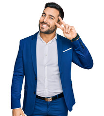 Wall Mural - Young hispanic man wearing business jacket doing peace symbol with fingers over face, smiling cheerful showing victory