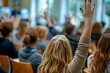 © Maelgoa - Back view of individuals raising their hands during a conference