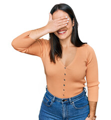 Sticker - Young hispanic woman wearing casual clothes smiling and laughing with hand on face covering eyes for surprise. blind concept.