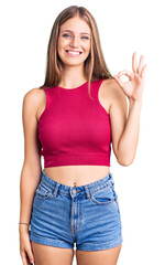 Wall Mural - Young beautiful blonde woman wearing elegant summer shirt smiling positive doing ok sign with hand and fingers. successful expression.