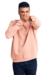 Poster - Young hispanic man wearing casual clothes laughing at you, pointing finger to the camera with hand over mouth, shame expression