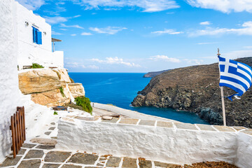 Terrace of Kastro village with white houses and Greek flag and view of sea coast, Sifnos island, Greece