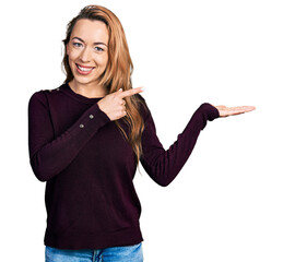 Canvas Print - Young caucasian woman wearing casual clothes amazed and smiling to the camera while presenting with hand and pointing with finger.