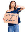 © Krakenimages.com - Young beautiful chinese girl holding we need a change banner with angry face, negative sign showing dislike with thumbs down, rejection concept