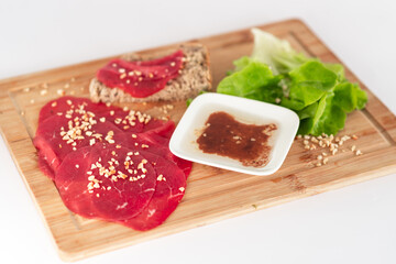 Wall Mural - A plate of meat and bread with a sauce on a wooden cutting board