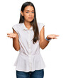 © Krakenimages.com - Beautiful hispanic woman wearing casual clothes clueless and confused expression with arms and hands raised. doubt concept.