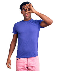 Wall Mural - African handsome man wearing casual clothes and glasses doing ok gesture shocked with surprised face, eye looking through fingers. unbelieving expression.