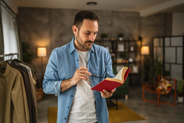 Wall Mural - Portrait of adult caucasian man with eyeglasses read book at living room happy and relax