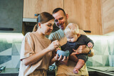 Fototapeta Łazienka - Young parents, mom and dad, feed the baby with complementary food for the first time. Baby's first complementary food. Food for a child