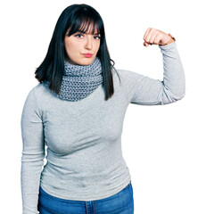 Poster - Young hispanic plus size woman wearing winter scarf strong person showing arm muscle, confident and proud of power