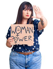 Sticker - Young plus size woman holding woman power banner with open hand doing stop sign with serious and confident expression, defense gesture