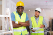 © JackF - Portrait of african-american man builder confused by his co-worker, european man, standing in background and quarreling.