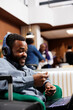 © DC Studio - African American businessman wearing headphones using laptop for video call, waiting in hotel lounge area for check-in. Smiling black guy entrepreneur participating in virtual meeting while traveling