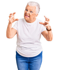 Wall Mural - Senior beautiful woman with blue eyes and grey hair wearing casual white tshirt shouting frustrated with rage, hands trying to strangle, yelling mad