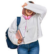© Krakenimages.com - Hispanic woman with pink hair wearing student backpack and headphones smiling cheerful playing peek a boo with hands showing face. surprised and exited