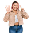© Krakenimages.com - Hispanic woman with pink hair wearing casual clothes showing and pointing up with fingers number six while smiling confident and happy.