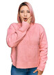 © Krakenimages.com - Hispanic woman with pink hair wearing casual winter sweater looking fascinated with disbelief, surprise and amazed expression with hands on chin