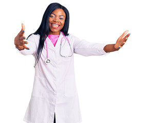 Canvas Print - Young african american woman wearing doctor stethoscope looking at the camera smiling with open arms for hug. cheerful expression embracing happiness.