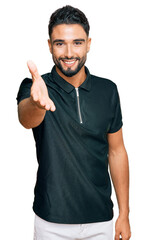 Canvas Print - Young man with beard wearing sportswear smiling friendly offering handshake as greeting and welcoming. successful business.