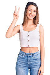 Wall Mural - Young beautiful girl wearing casual sleeveless t shirt showing and pointing up with fingers number two while smiling confident and happy.
