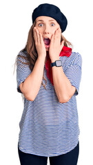 Poster - Young beautiful blonde woman wearing french beret and striped t-shirt afraid and shocked, surprise and amazed expression with hands on face