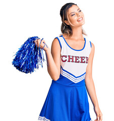 Canvas Print - Young beautiful woman wearing cheerleader uniform looking away to side with smile on face, natural expression. laughing confident.