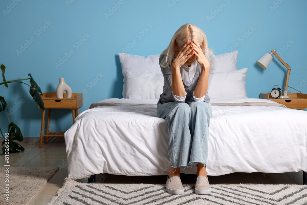 Depressed mature woman sitting in bedroom
