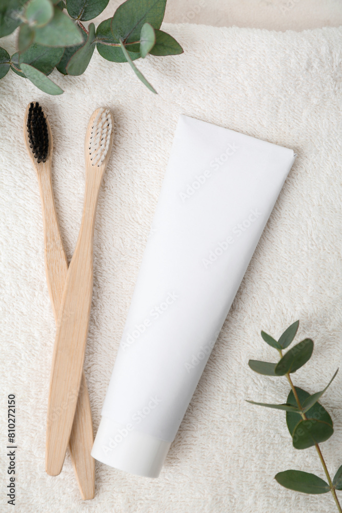 Wooden toothbrushes, paste and eucalyptus branches on white clean towel