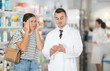 © JackF - Young girl suffering from pain is asking pharmacist holding a box of medicine for advice in chemist's shop