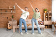 © Pixel-Shot - Young couple in headphones dancing on green carpet at home