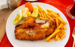 Piece of deep-fried fish filet in crispy coating of egg and breadcrumbs served with side dish of french fries and pickled vegetables. Turkish cuisine