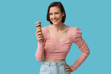 Poster - Happy young woman with sweet ice-cream in waffle cone on blue background