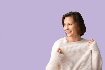 Poster - Happy young woman in stylish white sweater on lilac background