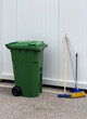 Plastic closed trash bin with cleaning equipment broom and brush outdoors in the street