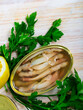 Picture of tasty sea natural navajas in open tin can served with greens and lemon at table