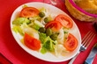 Traditional Valencian salad with lettuce leaves, chopped tomatoes, onions and olives, seasoned with olive oil