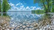 A serene panorama of a pebbly shore of a pristine lake flanked by lush green trees under a stunningly clear blue sky with scattered clouds