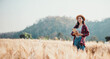 © Satori Studio - Woman stands holding a notebook in a vast wheat field, with the backdrop of a clear blue sky and distant hills.