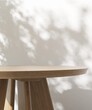 Round wooden table podium in dappled sunlight, tree leaf shadow on white wall for modern, luxury fashion, beauty, cosmetic, skincare, body care, product background 3D