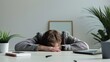 © Natalia S. - A man sleeps at his desk in the office, with his head on the table and his hands under his head next to his laptop. Professional burnout, work without rest, workaholism