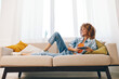 © SHOTPRIME STUDIO - Happy woman holding mobile phone, enjoying online games and reading messages on sofa at home
