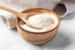 Psyllium husk in spoon and wood bowl, fiber food for diet  on white marble table
