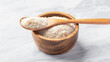 Psyllium husk in spoon on wooden bowl on white marble table